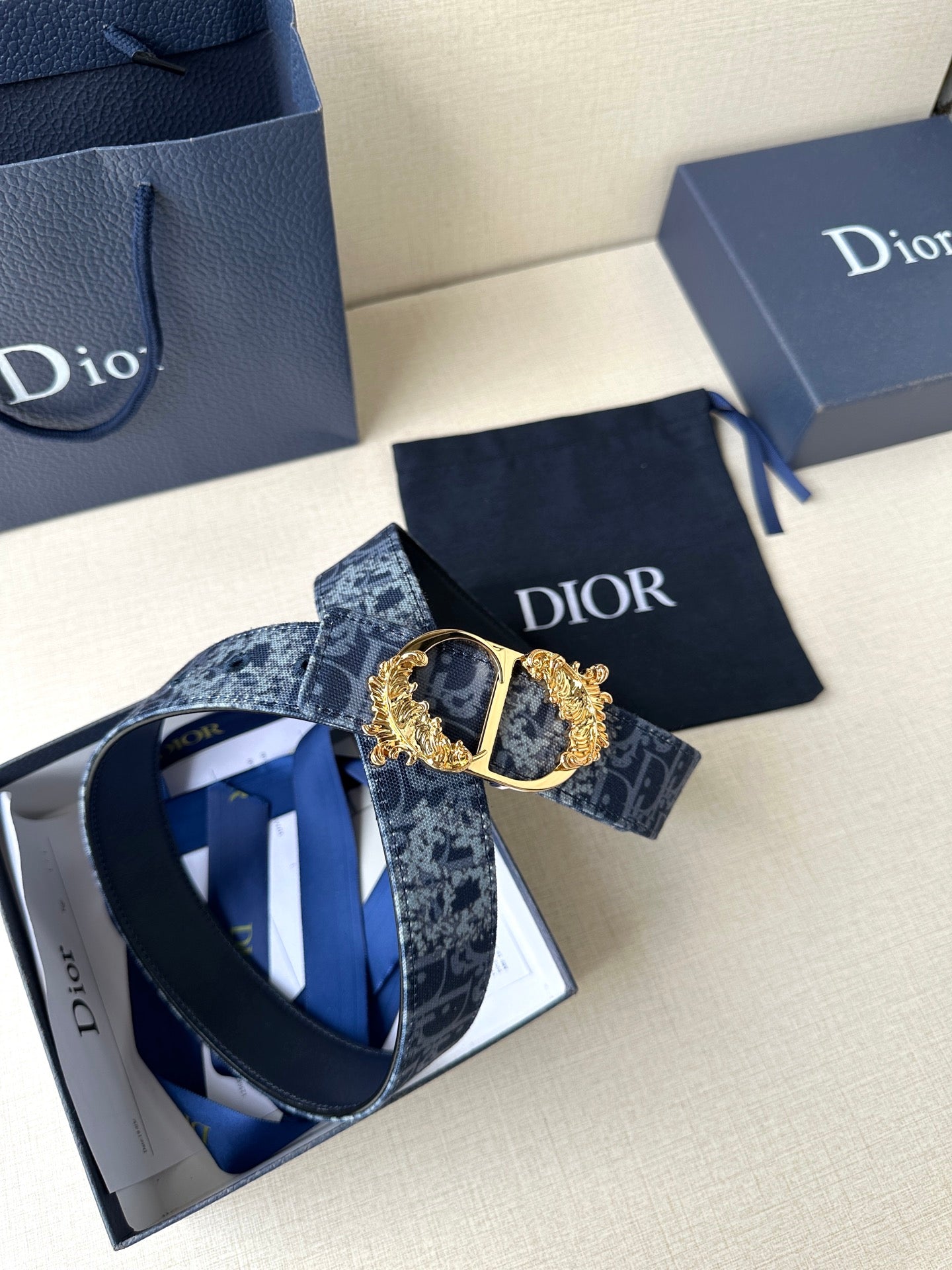 Dior belt laid flat with dark blue monogram strap and gold buckle