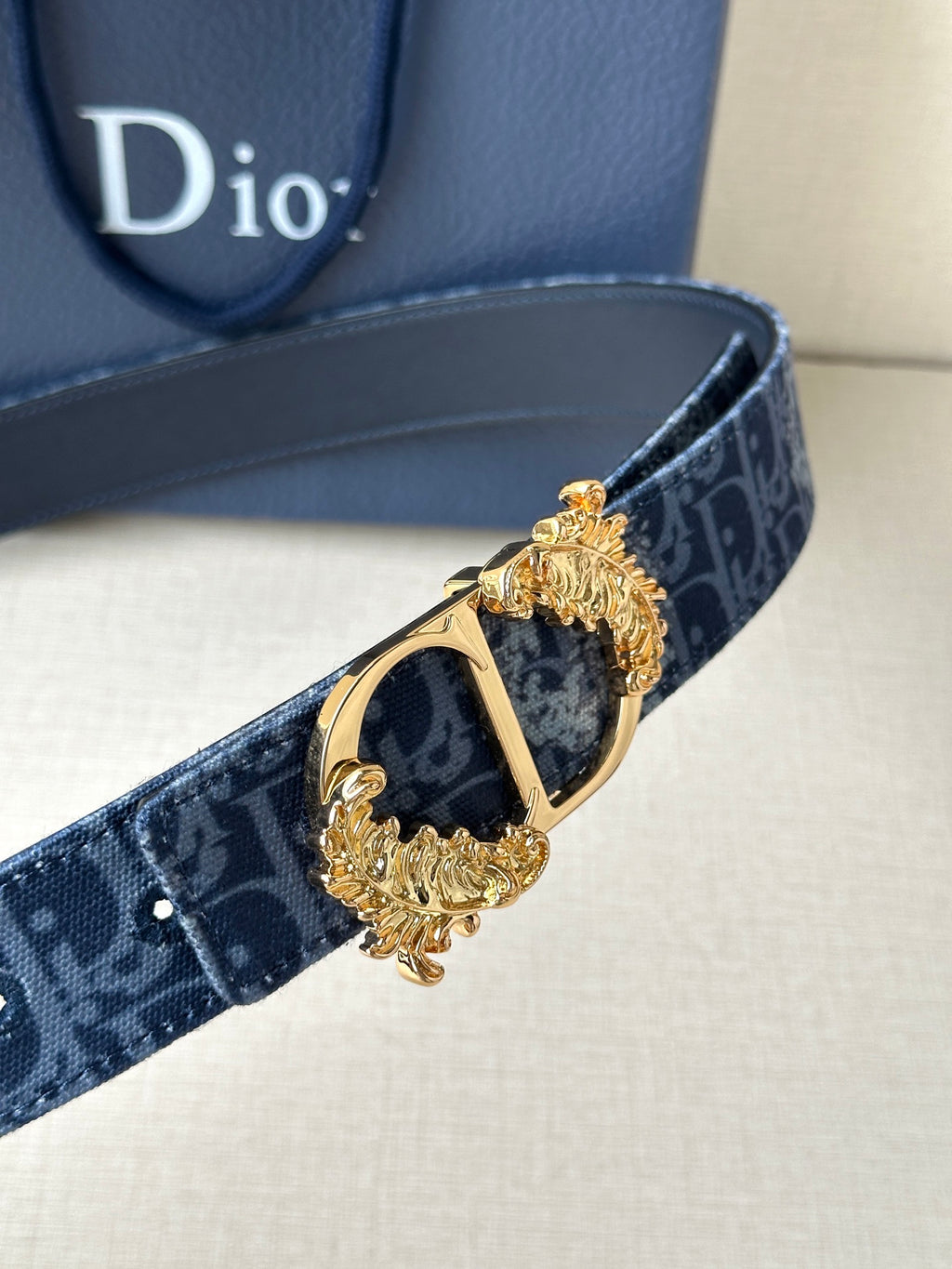 Dior belt close-up: dark blue monogram strap with gold buckle and square frame