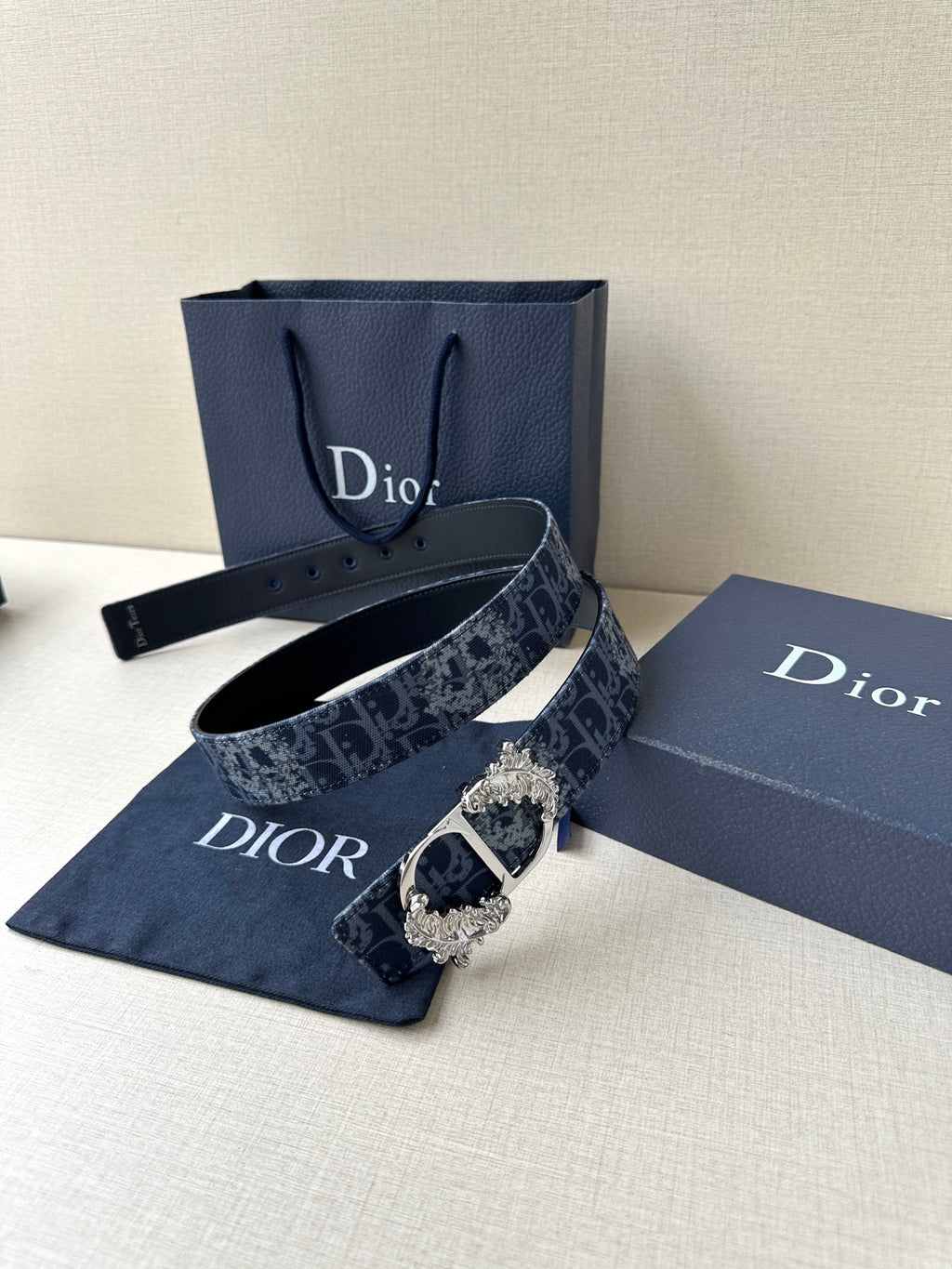 Dior belt with dark blue monogram strap, gold buckle, and perforated tail end