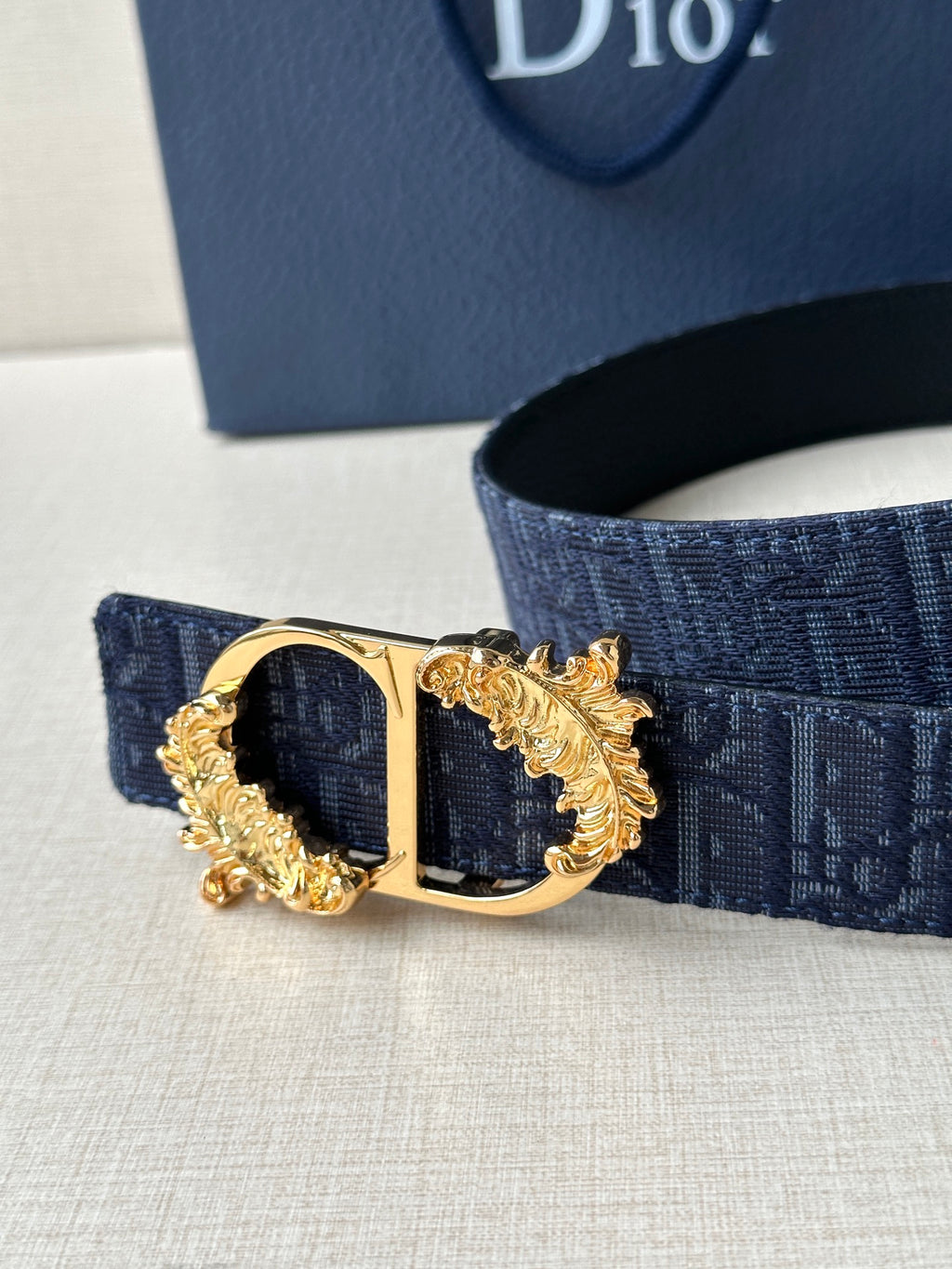 Dark blue Dior belt close-up of gold-tone buckle with oval center