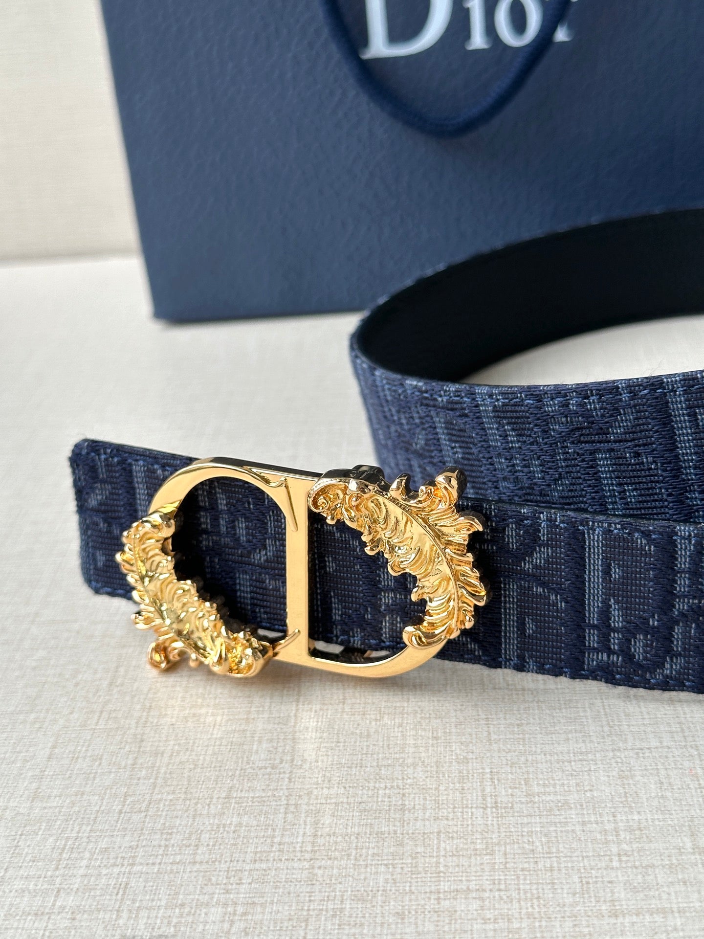 Dark blue Dior belt close-up of gold-tone buckle with oval center