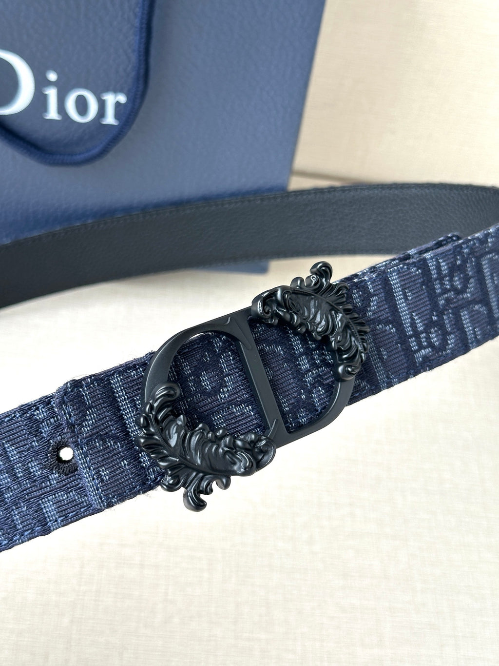 Dior belt detail: dark blue strap with black oval buckle and metal embellishment