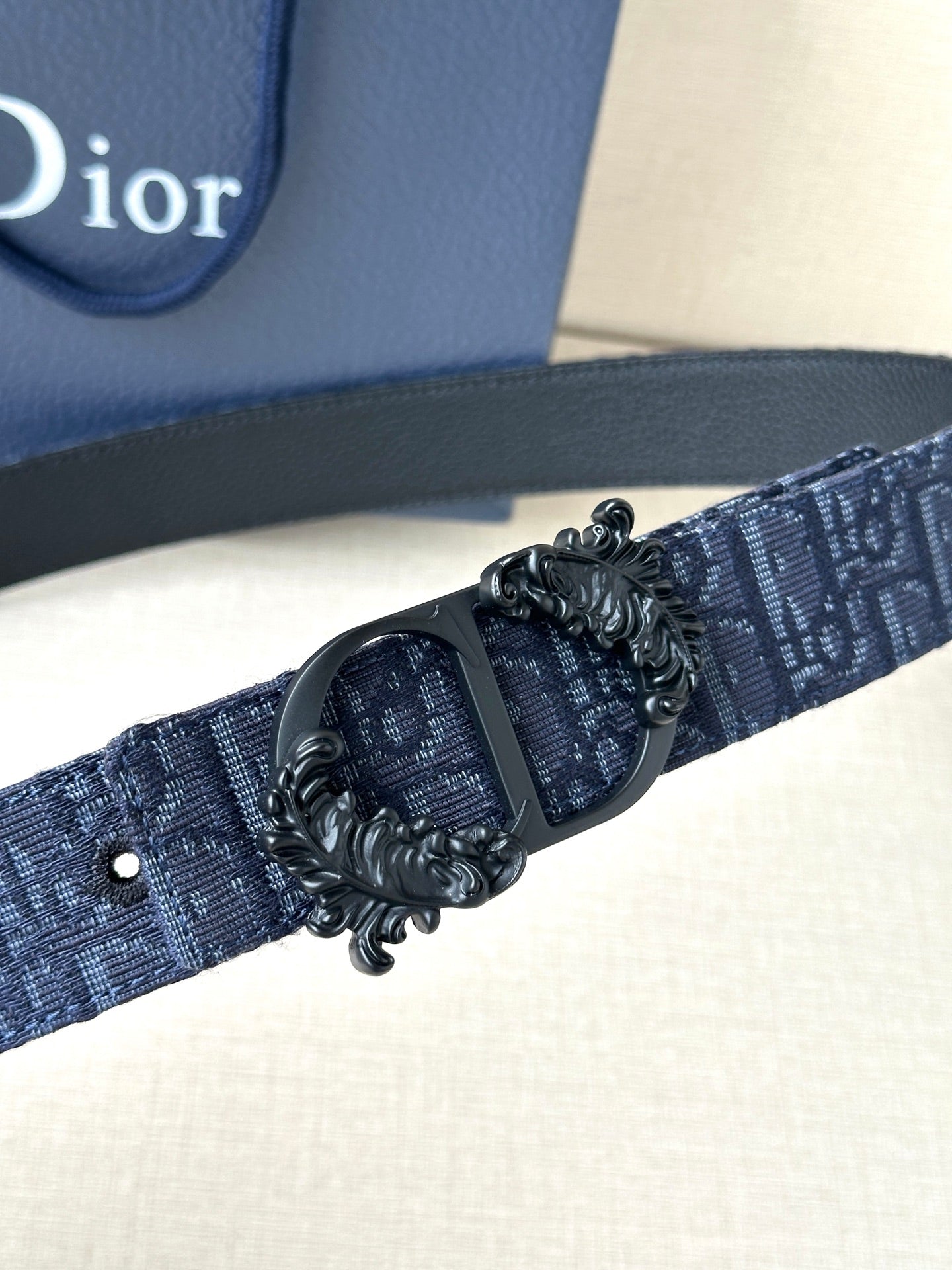 Dior belt detail: dark blue strap with black oval buckle and metal embellishment