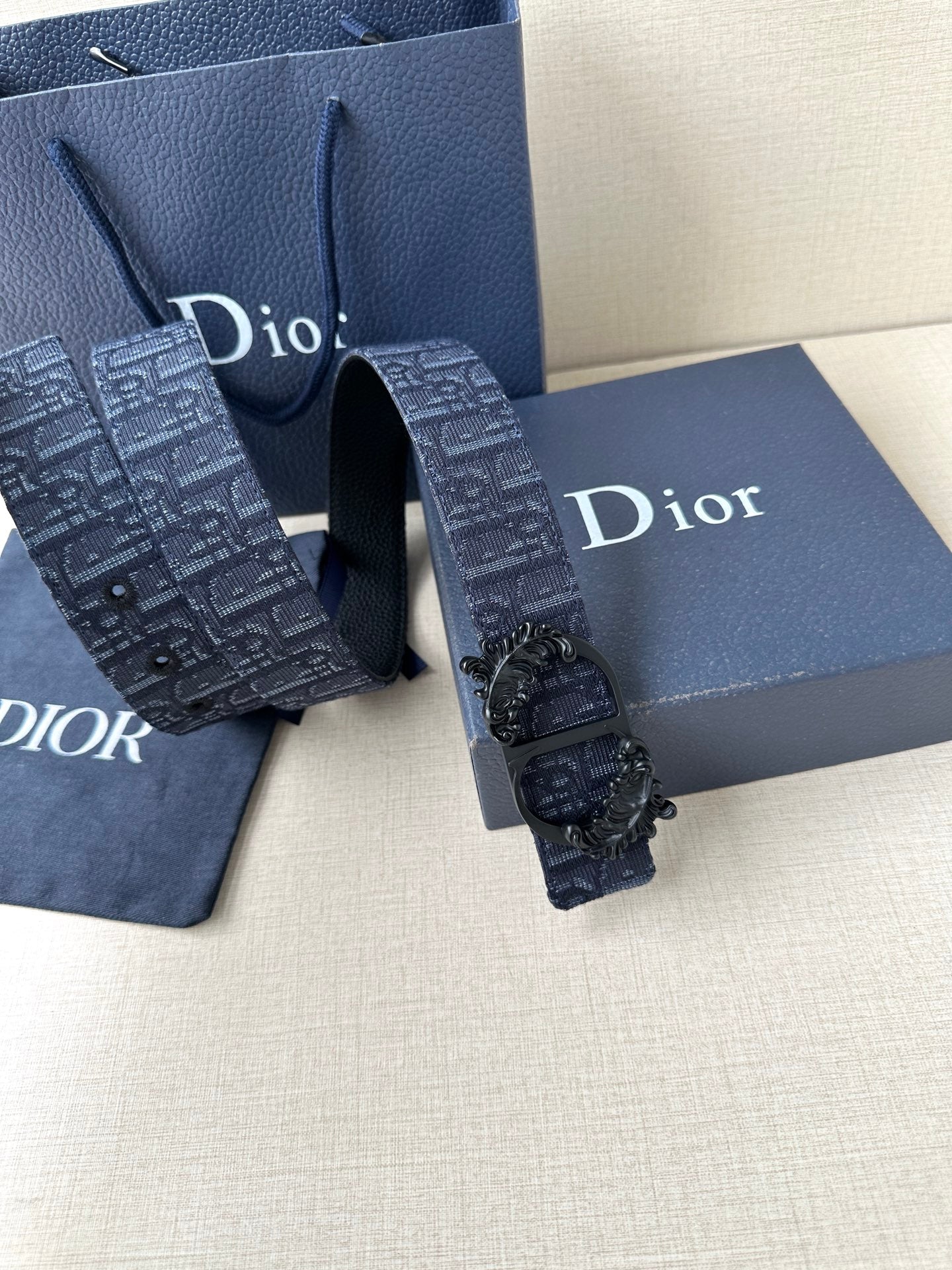 Dior belt close view: dark blue monogram-style strap with black sculpted buckle