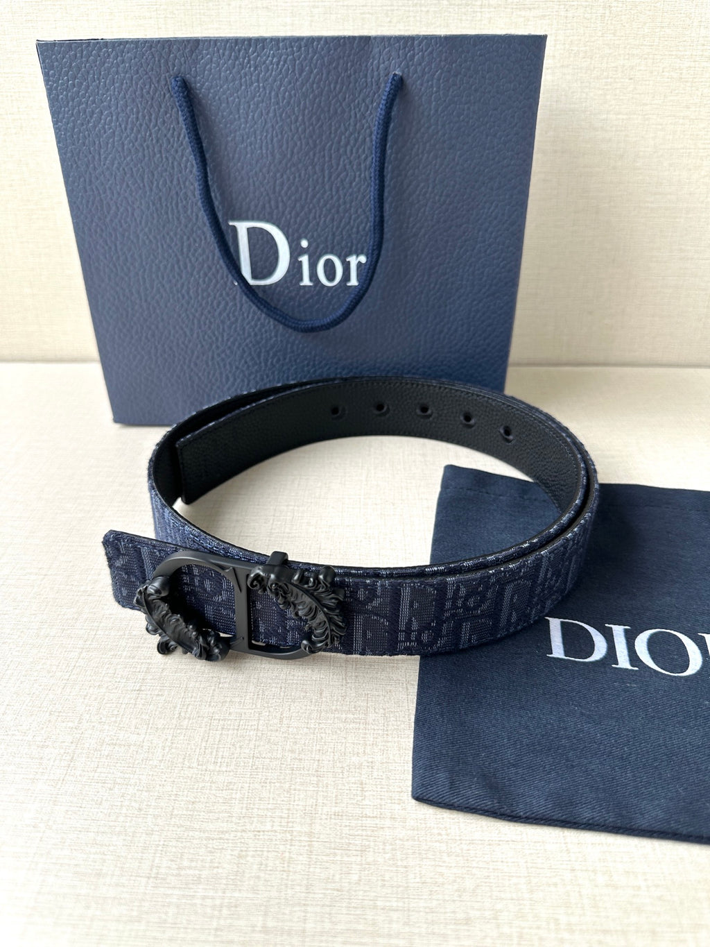 Dior belt with dark blue strap, black buckle centerpiece, and punched adjustment holes