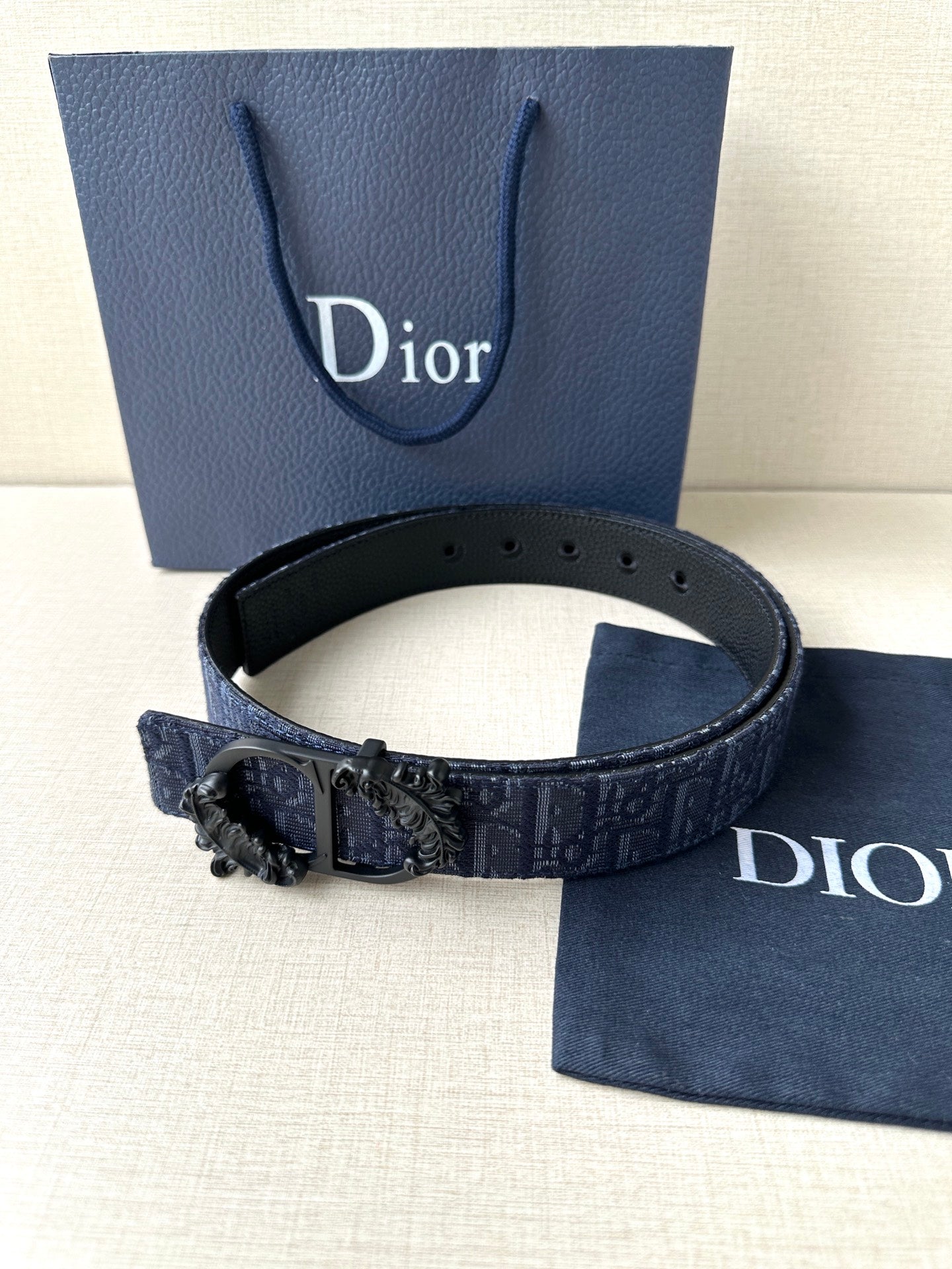 Dior belt with dark blue strap, black buckle centerpiece, and punched adjustment holes