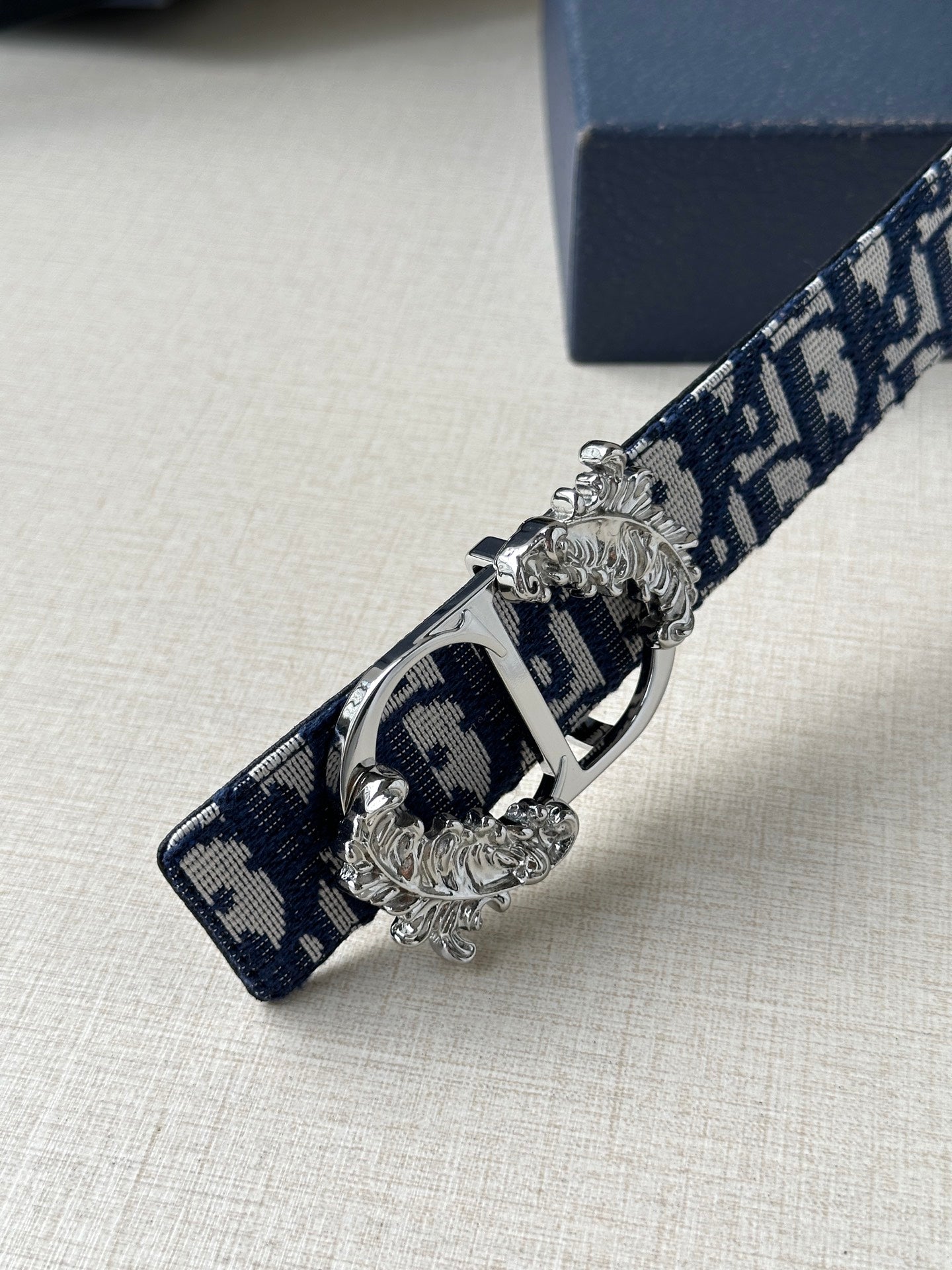 Navy logo belt with silver-toned buckle hardware and ornate decorative clasp