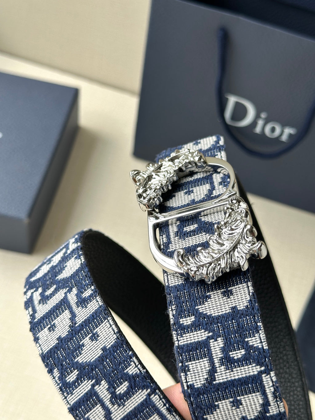 Dior belt featuring navy logo strap with silver-toned ornate buckle and clasp