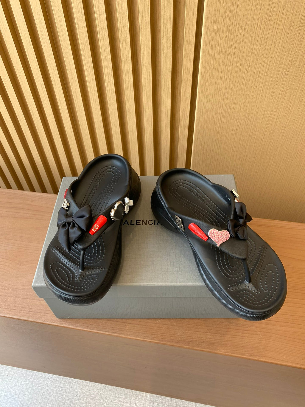 Black sandals with heart charm and braided strap accents, cushioned thong footbed