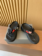 Black sandals with heart charm and braided strap accents, cushioned thong footbed