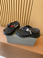 Black flip-flops with heart and bow charms, textured strap and sculpted footbed