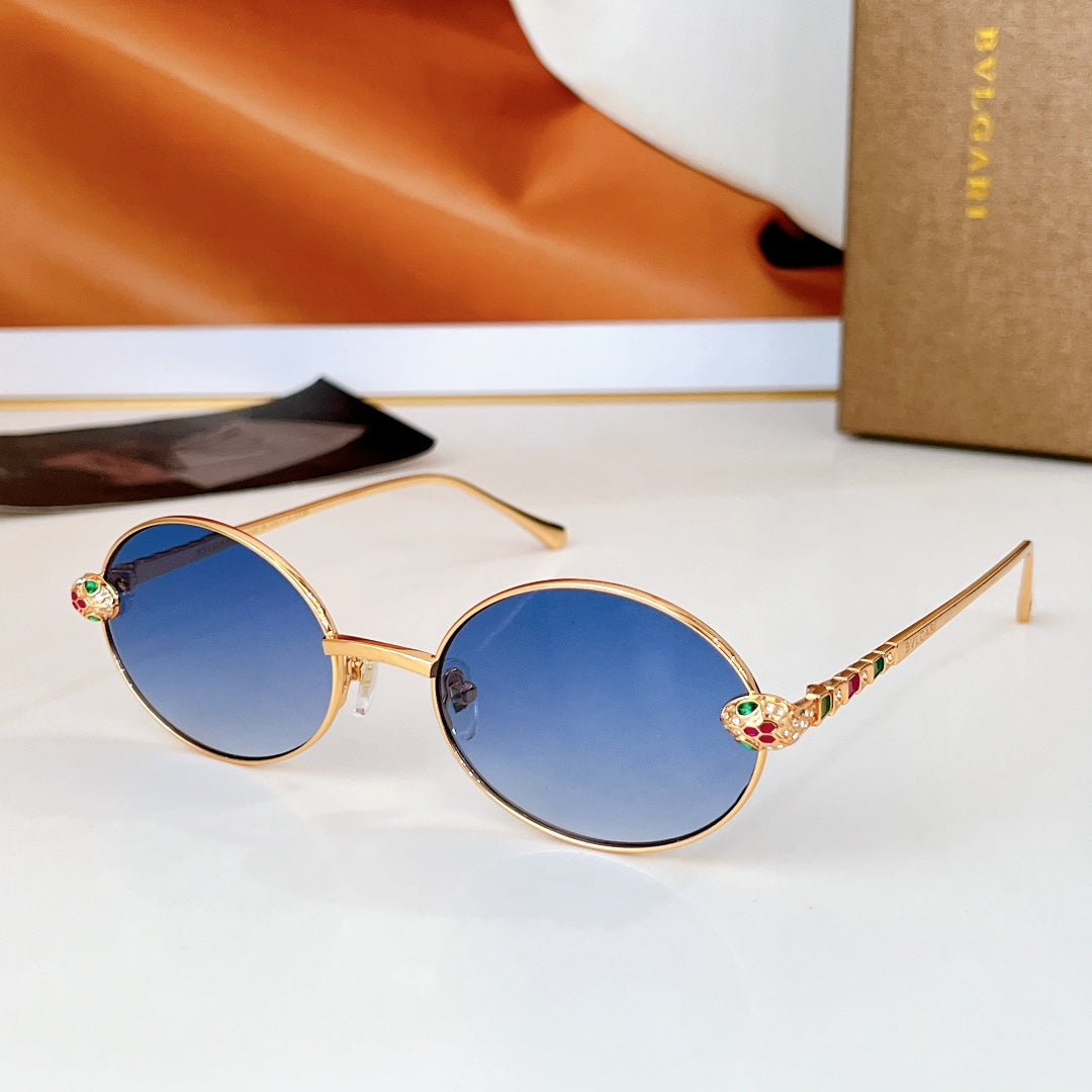 Gold round sunglasses with blue lenses and multicolor gemstone-like temple decorations