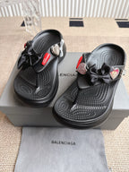 Balenciaga black sandals with bow straps, heart-shaped charm, and textured footbed