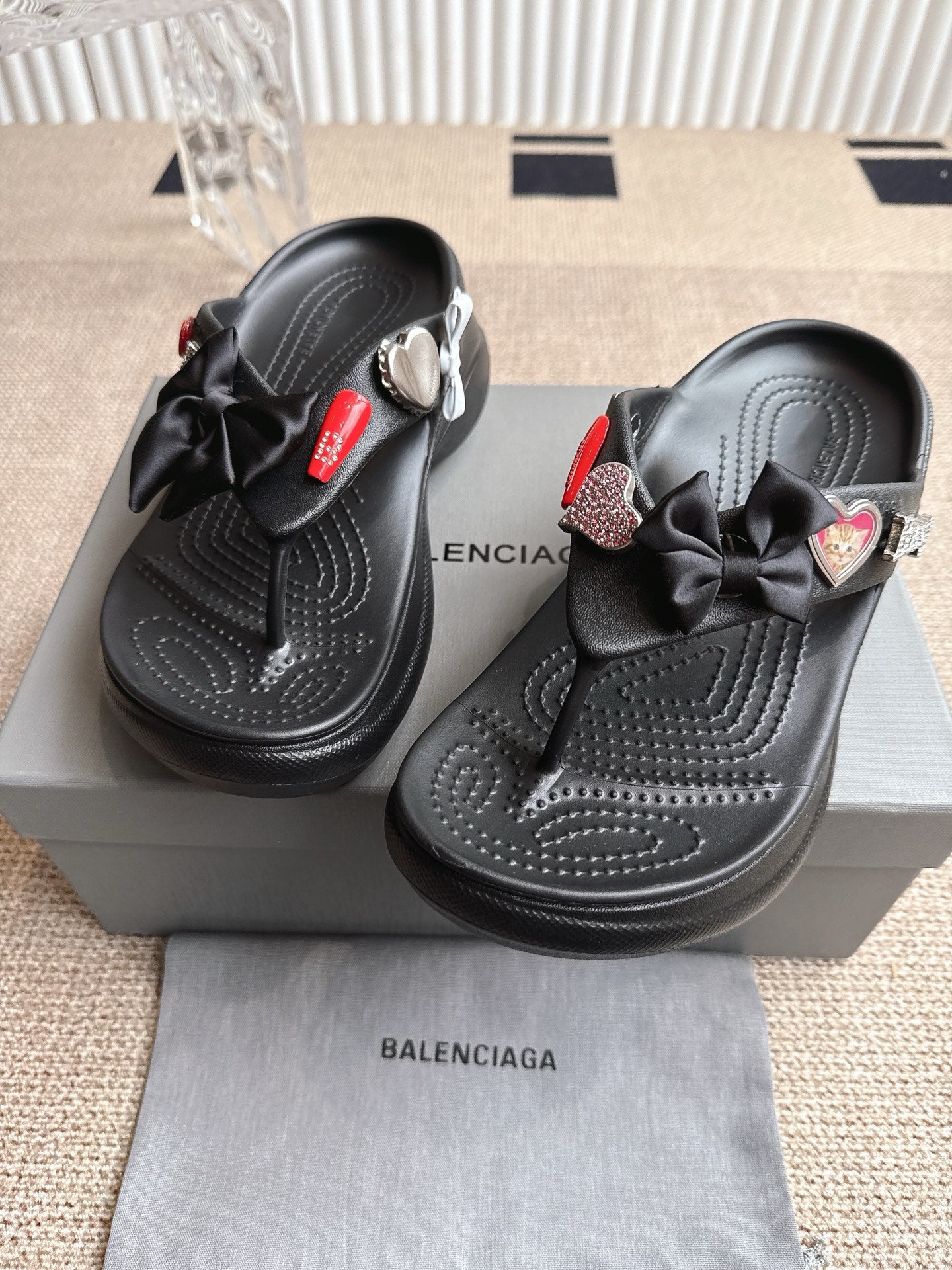 Balenciaga black sandals with bow straps, heart-shaped charm, and textured footbed