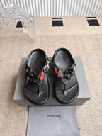Balenciaga black sandals with bow detail, textured straps, and red accent on upper