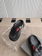Balenciaga black sandals with bow straps, textured sole, and heart-shaped charm detail