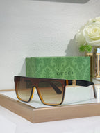 Gucci sunglasses with dark frames and amber lenses, gold logo on side
