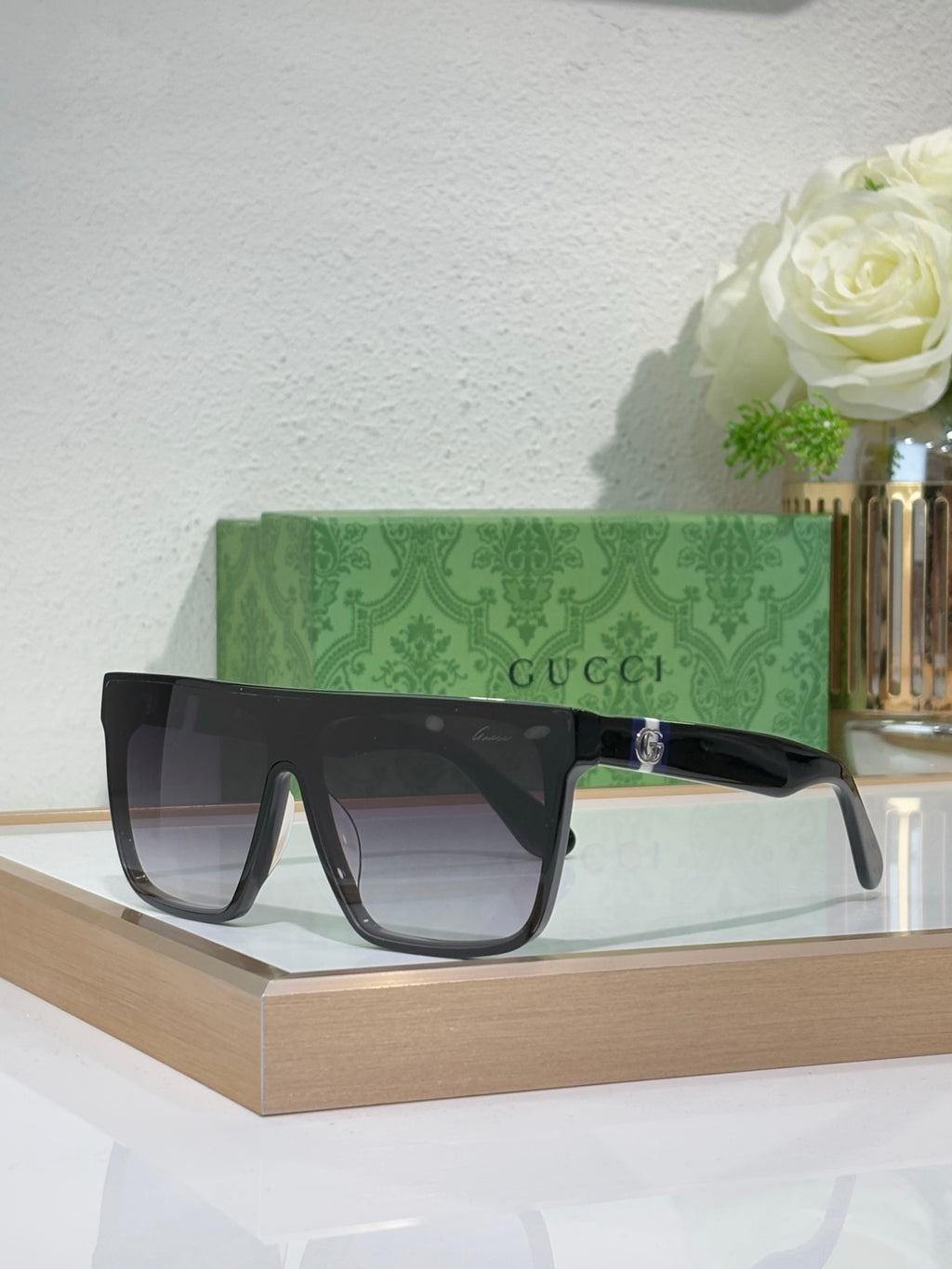 Gucci sunglasses with dark frames and clear gray lenses, gold logo on temple