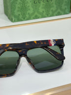 Gucci sunglasses close-up with tortoise frames and green lenses, colorful logo on top bar