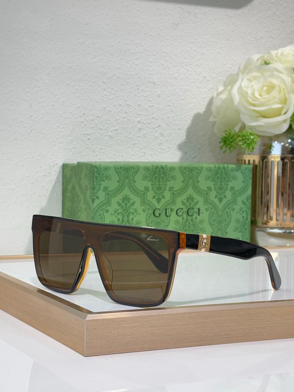 Gucci sunglasses with dark frames and brown lenses, gold detail on bridge