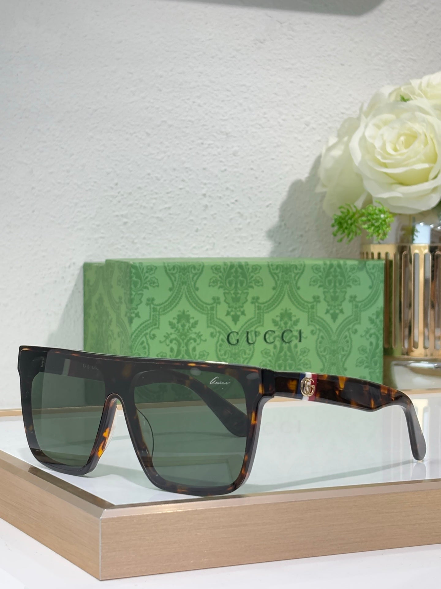 Gucci sunglasses with dark frames and green-tinted lenses, gold temple detail
