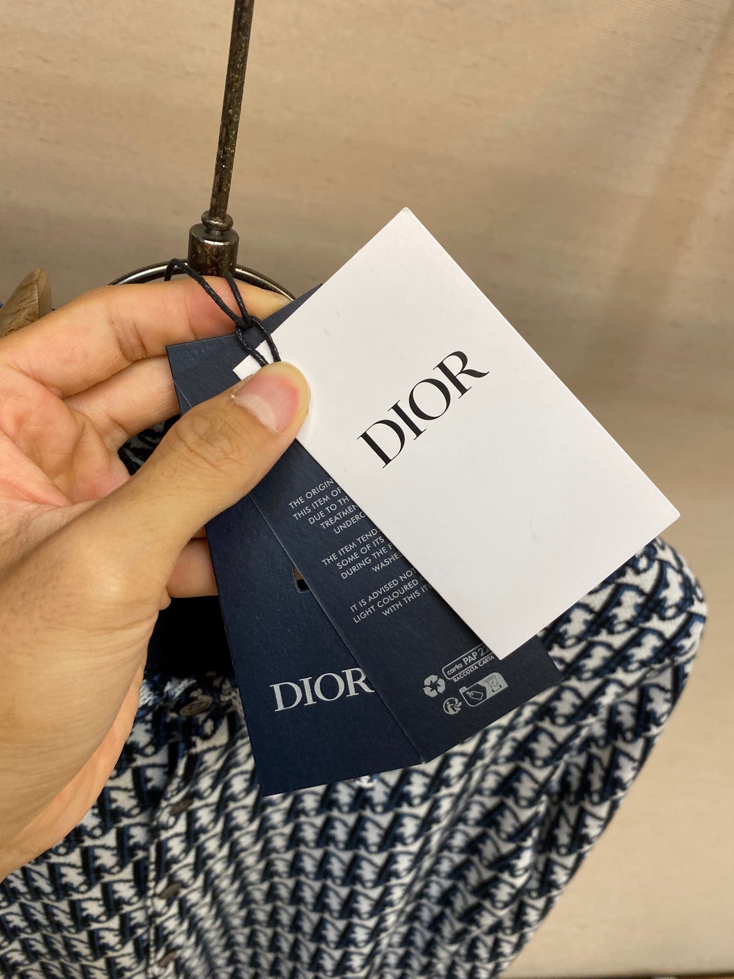 Dior clothing tags attached to patterned shirt on hanger