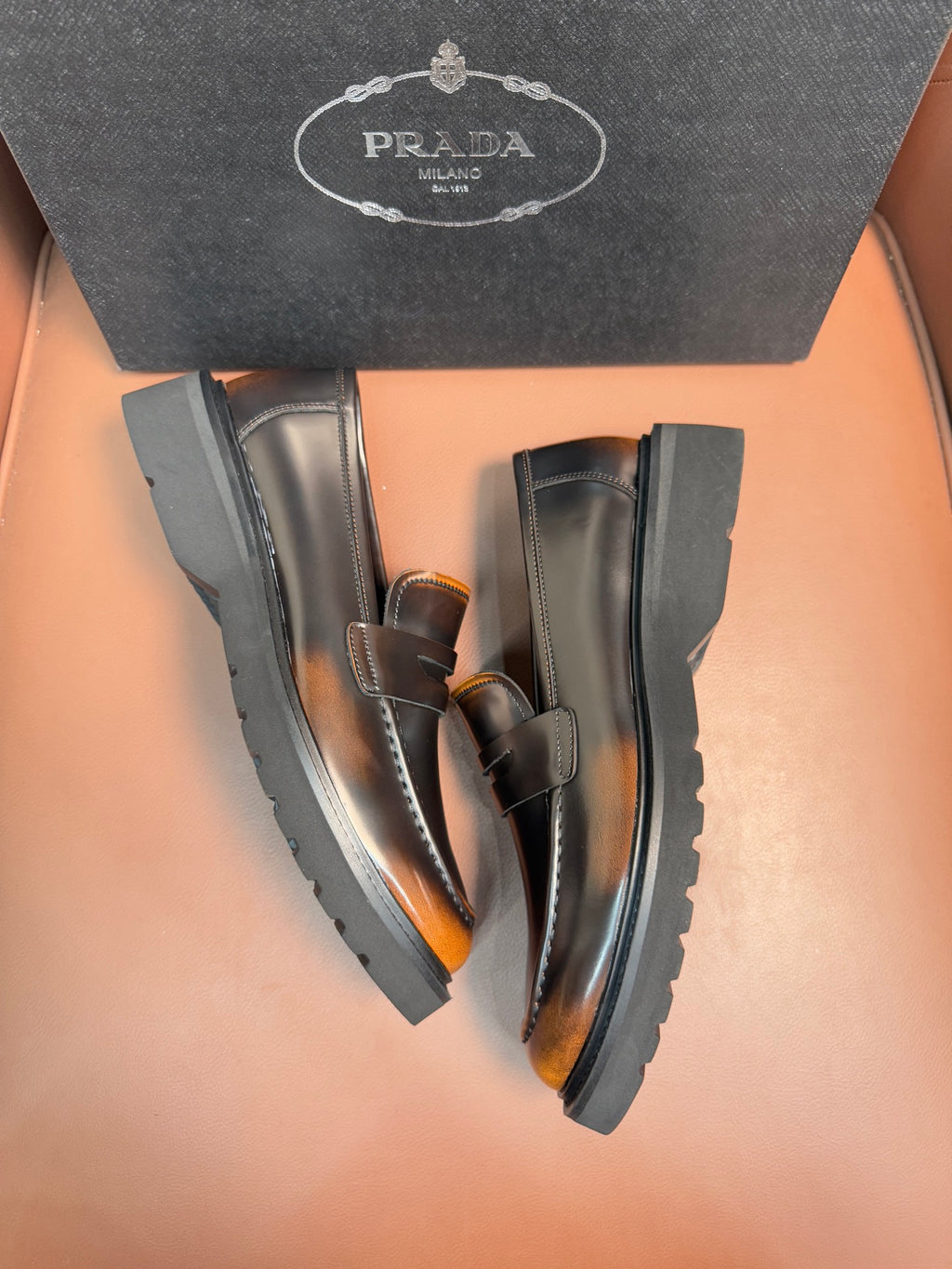 Dark leather loafer pair, apron strap and stitched moc toe, chunky rubber soles