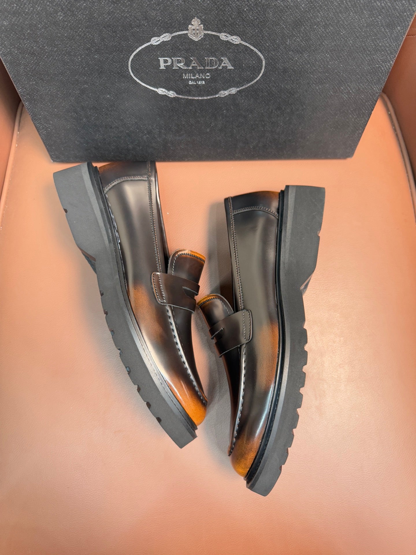 Dark leather loafer pair, apron strap and stitched moc toe, chunky rubber soles
