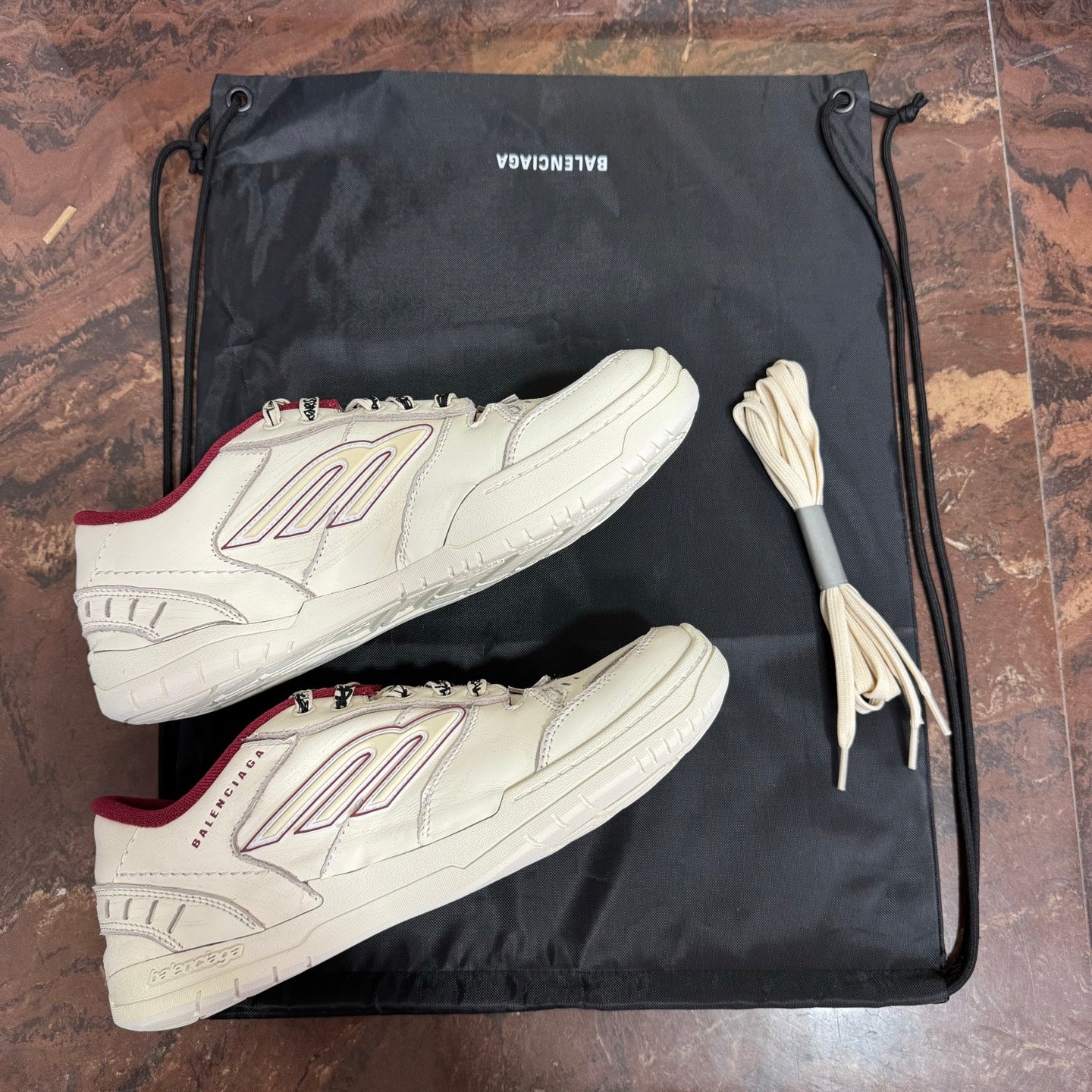 White Balenciaga lace-up sneakers with red heel accents, two pairs shown