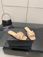 Beige braided-strap slide sandals on black display box, open toe, flat sole