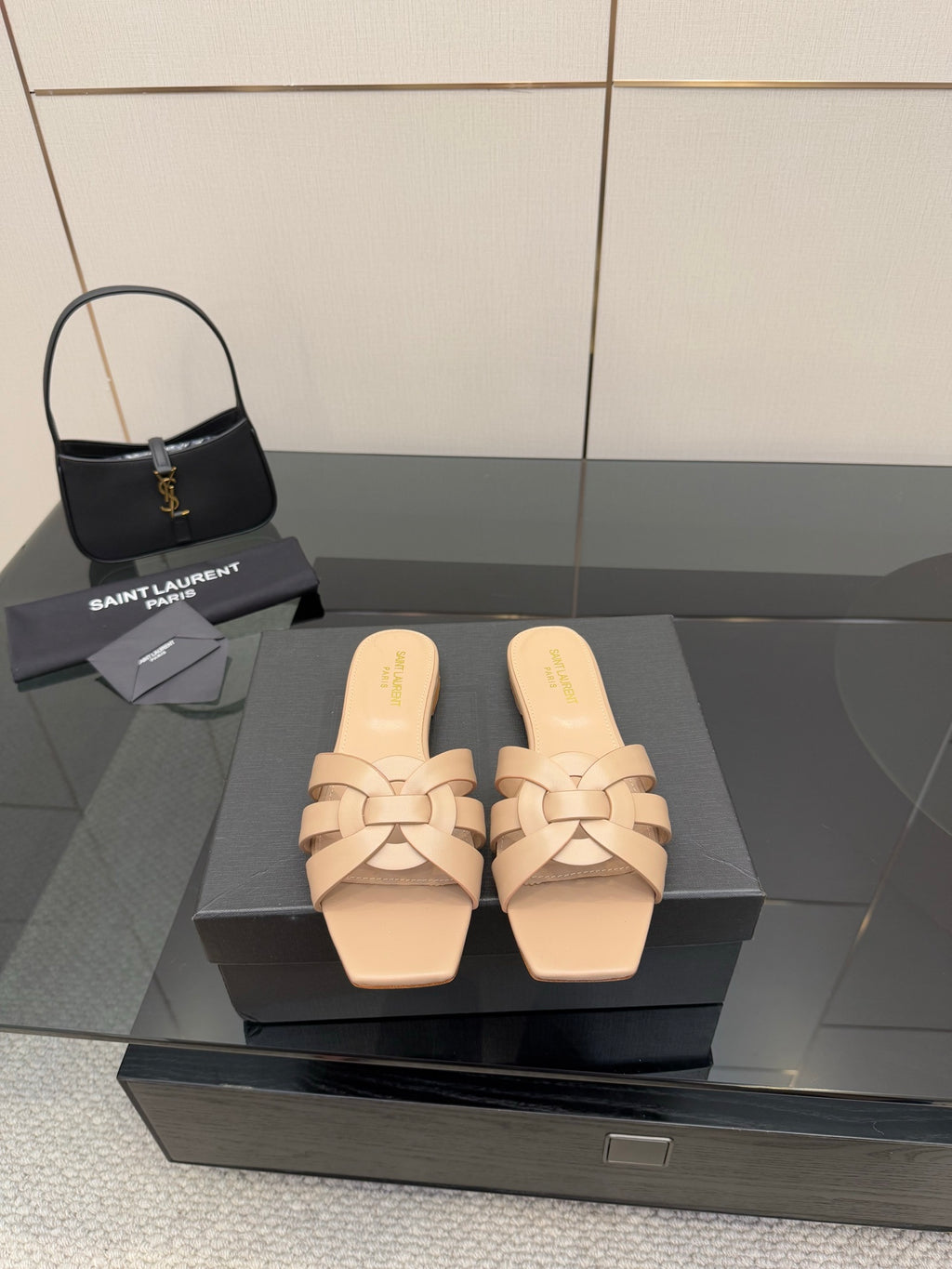 Beige woven-strap slide sandals on black display box, open toe, low flat heel