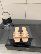 Beige woven-strap slide sandals on black display box, open toe, low flat heel