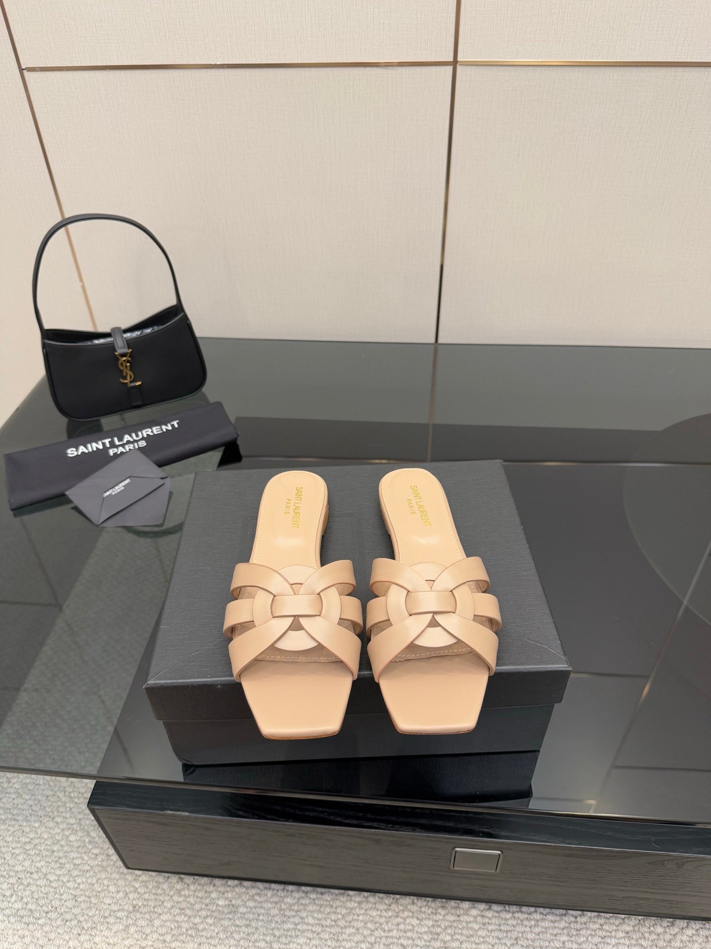 Beige woven-strap slide sandals on black display box, open toe, low flat heel