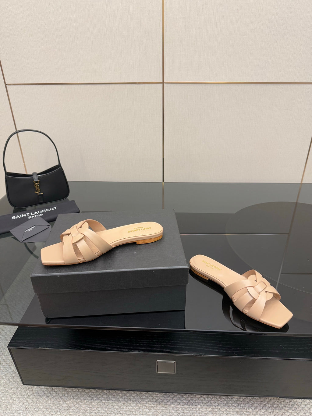 Beige braided-strap slide sandals on black display box, open toe, flat sole