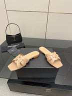 Beige woven-strap slide sandals on black display box, open toe, flat heel