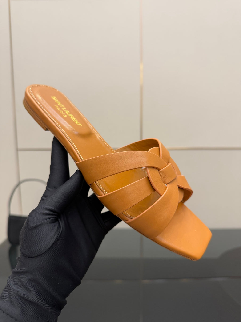 YSL women's orange woven slide sandal close-up, crossover straps on flat sole