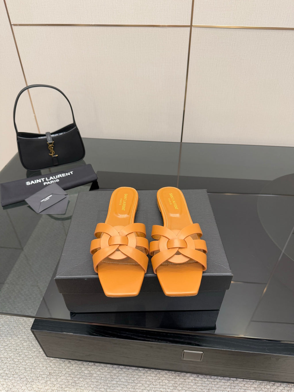YSL women's orange woven slide sandals on display, flat slip-on sole