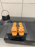 YSL women's orange woven slide sandals on display, flat slip-on sole