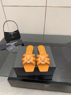 YSL women's orange woven slide sandals on display, flat slip-on sole