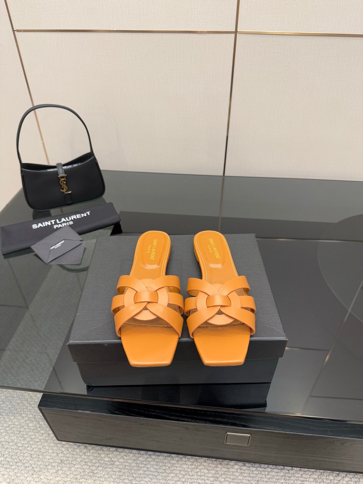 YSL women's orange woven slide sandals on display, flat slip-on sole
