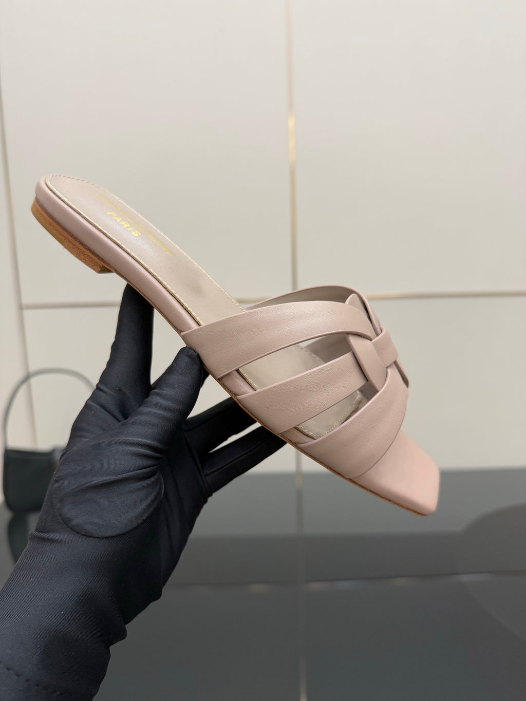 Women's light beige braided slide sandal held in hand, open toe