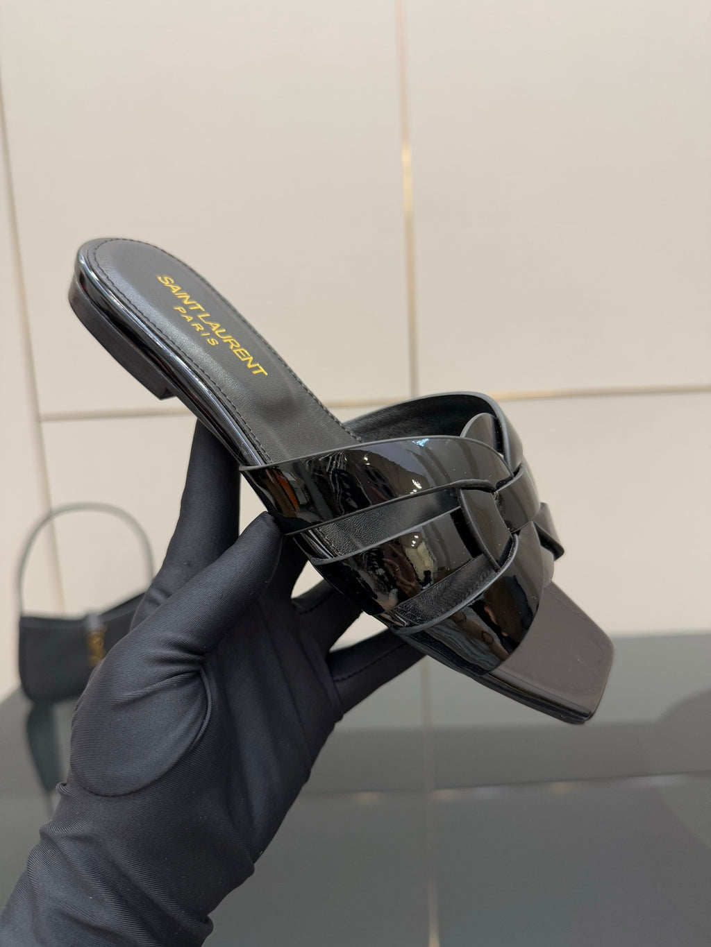 Close-up of black slide sandal with yellow logo text on the footbed and heel view