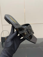 Close-up of black slide sandal with yellow logo text on the footbed and heel view