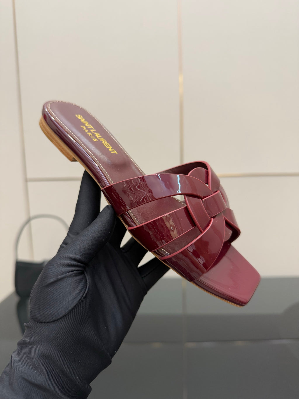 YSL pink patent mule in hand, open-toe slide sandal with bow straps and low heel