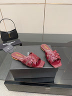 YSL pink bow mules on display, glossy open-toe slip-on sandals with pink strap bows