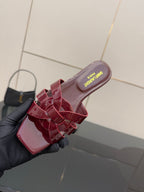 YSL pink bow mule in hand, open-toe slide sandal with glossy straps and cushioned footbed