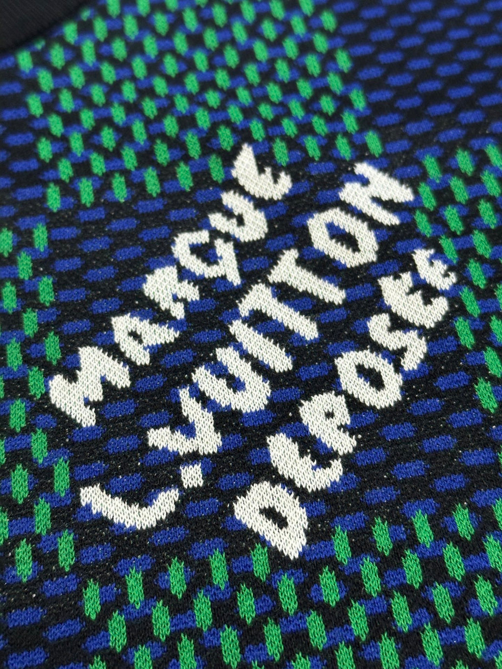 Louis Vuitton embroidered slogan on blue and green check T-shirt, close-up of white text.
