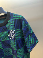 Louis Vuitton T-shirt sleeve detail with blue and green check pattern and white embroidered text.