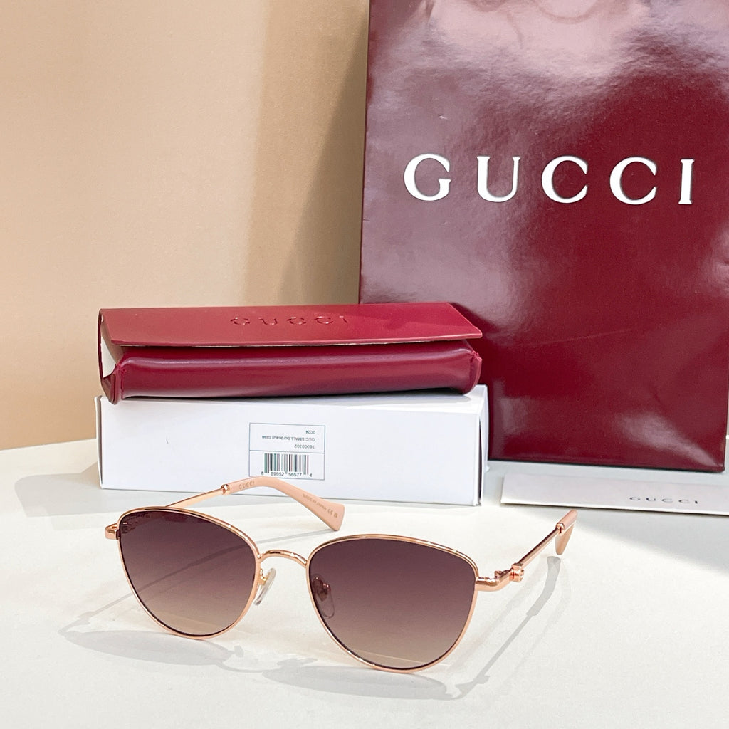 Sunglasses with gold frame, brown tinted lenses, and pink temples.