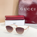 Sunglasses with gold frame, brown tinted lenses, and pink temples.